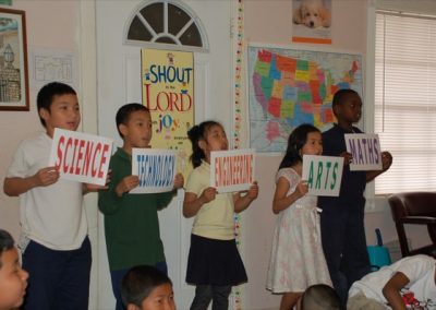 A group of children holding signs in front of a wall.