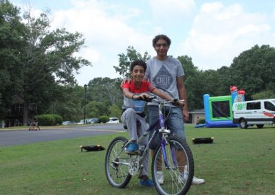 A man and boy on a bike in the grass.