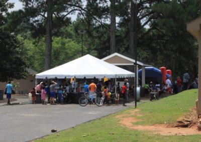 A group of people standing around an outdoor tent.