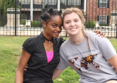 Two young women posing for a picture in front of a building.