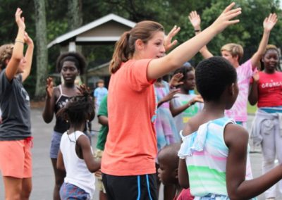 A woman in an orange shirt is waving