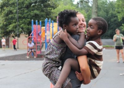 A woman holding two children on her back.