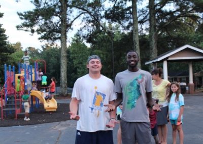 Two men standing next to each other in front of a playground.