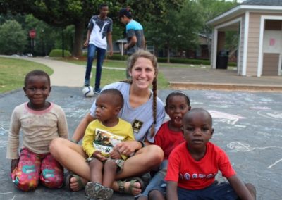 A woman sitting on the ground with some children.