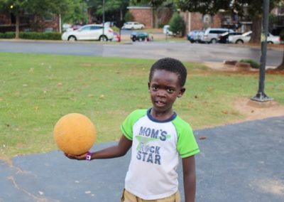 A young boy holding an orange ball in his hand.