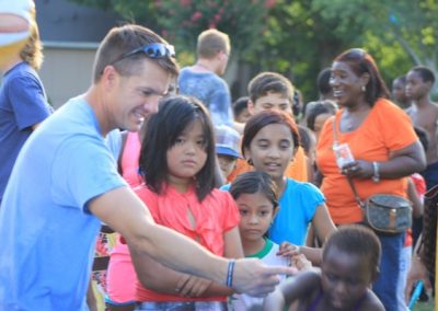 A man is handing out flyers to children.