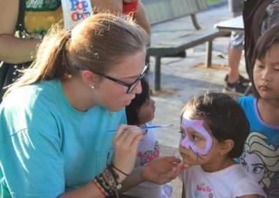 A woman is painting the face of a child.