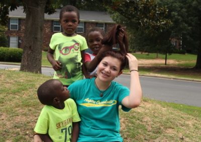 A woman sitting on the grass with some kids.