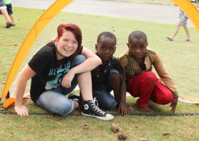 A woman sitting on the ground with two boys.