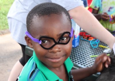 A young boy wearing glasses and smiling for the camera.