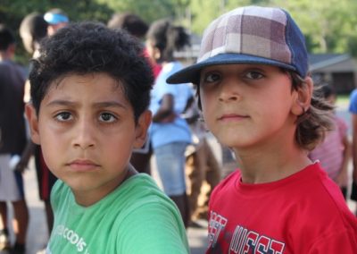 Two boys are standing together in a crowd.