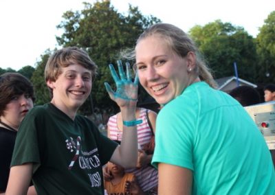 Two people with blue hands painted on their fingers.