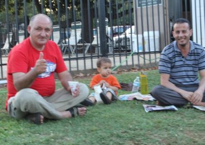 A man and two women sitting on the grass with a baby.