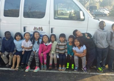 A group of children sitting in front of a van.