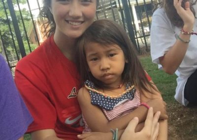 A young girl holding onto her arm with another girl.